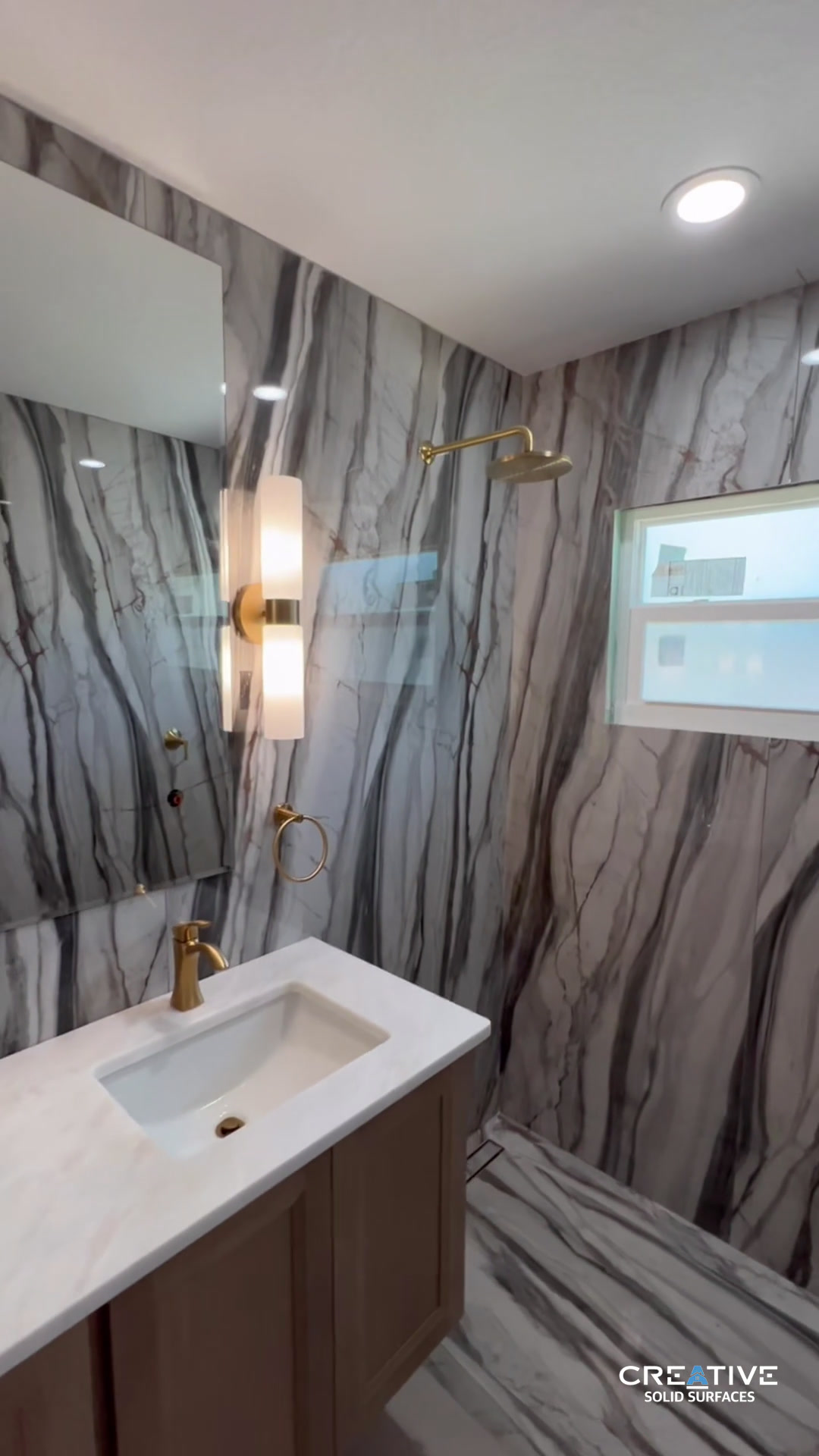 Marble-look shower + double vanity Gold fixtures, porcelain walls,...